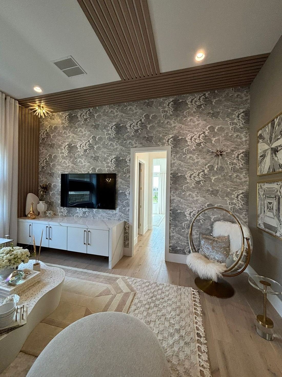 Hotel suite living room with cloud wallpaper, wood slat ceiling detail and light oak floors